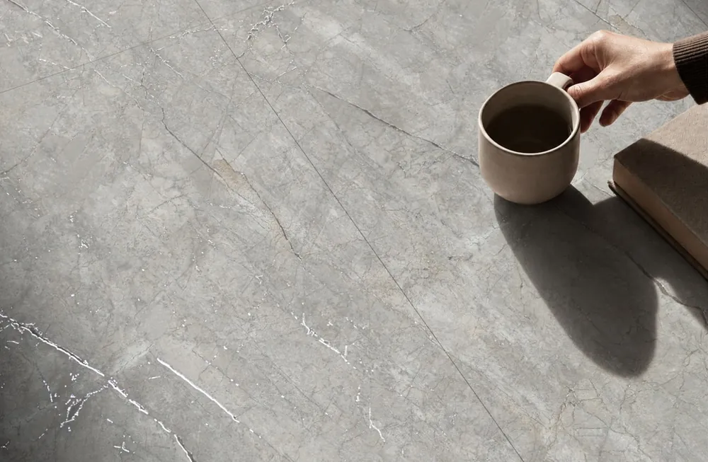 Luxe Lahim Grey stone tile with a hand holding a cup
